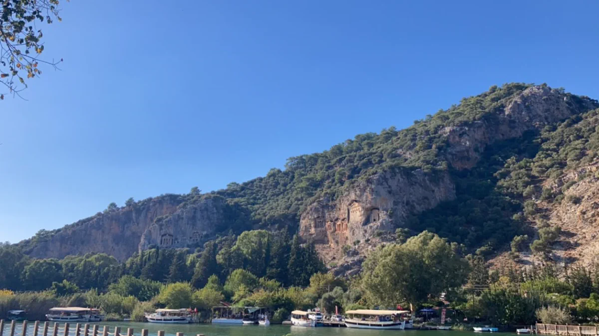 Boats at the Dalyan quay with the rock tombs rising behind them Boats at the Dalyan quay with the rock tombs rising behind them